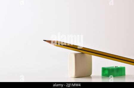 Base conceptuelle de l'enseignement dans les écoles avec crayon, gomme et taille-crayon sur table et blanc isolé. Vue avant. Banque D'Images
