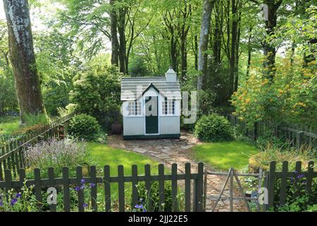 Une petite maison de jeux en bois pour enfants dans son propre petit jardin entouré d'une clôture de piquetage Banque D'Images