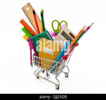 Concept de retour à l'école. Fournitures de bureau d'école et papeterie dans un chariot de magasinage isolé sur la couleur blanche. Banque D'Images