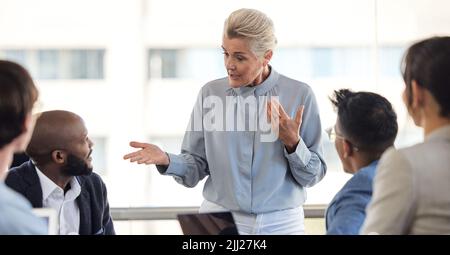 Elle se dit très précise sur les objectifs qu'elle veut atteindre. Une femme d'affaires senior ayant une réunion avec ses collègues dans un bureau. Banque D'Images