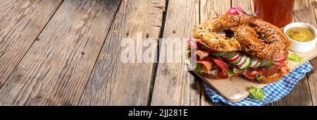 Sandwich au bagel Oktoberfest bretzel. Petit déjeuner Oktoberfest, recette de hamburger pour les fêtes de fête de la bière. Grand bretzel avec jambon, fromage, légumes frais, W Banque D'Images