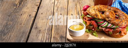 Sandwich au bagel Oktoberfest bretzel. Petit déjeuner Oktoberfest, recette de hamburger pour les fêtes de fête de la bière. Grand bretzel avec jambon, fromage, légumes frais, W Banque D'Images