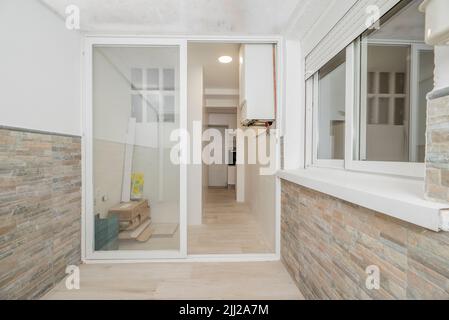 Terrasse avec fenêtres en aluminium blanc et verre dans la cuisine d'un appartement et toit en plastique semi-transparent et chaudière à gaz naturel Banque D'Images