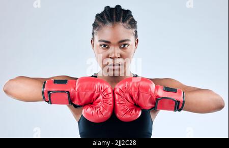 Je reprends mon pouvoir. Photo en studio d'une jeune femme sportive portant des gants de boxe tout en posant sur un arrière-plan de studio. Banque D'Images