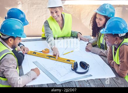 S'assurer que tout va selon le plan. Un groupe de travailleurs de la construction discutant des plans tout en travaillant sur un chantier. Banque D'Images