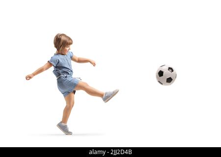 Prise de vue en longueur d'une petite fille qui donne un coup de pied à un ballon de football isolé sur fond blanc Banque D'Images