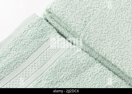 Draps ou serviettes de bain vert menthe pliés sur fond blanc. Gros plan de la texture, espace de copie Banque D'Images