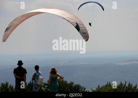 Kozakov, République tchèque. 22nd juillet 2022. Les touristes se tiennent sur la terrasse d'observation et regardent un parapente pendant une journée ensoleillée sur la colline de Kozakov en République tchèque.les Paragliders utilisent des thermiques pour leur vol. Le soleil chauffe la terre et la terre elle-même diffuse sa chaleur dans l'air environnant. À ce moment-là, une bulle thermique se forme et s'élève pour donner naissance à de vraies colonnes thermiques. (Credit image: © Slavek Ruta/ZUMA Press Wire) Banque D'Images