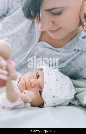 la mère joue avec son nouveau-né un jouet ours en peluche Banque D'Images