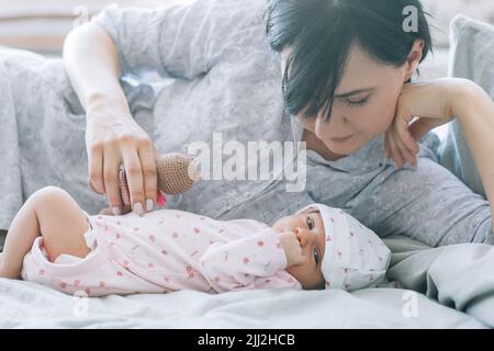 la mère joue avec son nouveau-né un jouet ours en peluche Banque D'Images