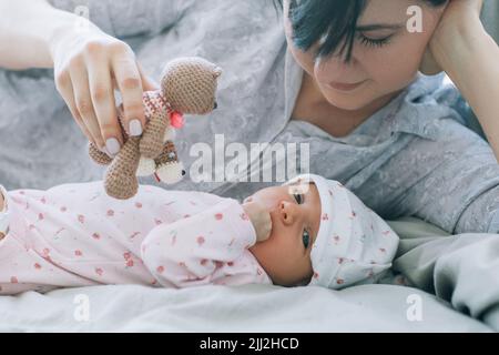 la mère joue avec son nouveau-né un jouet ours en peluche Banque D'Images
