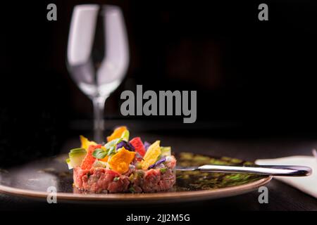 Une belle tartare de thon fraîchement préparée, avec des légumes doux/aigre, de la mayonnaise à la chaux, de la vinaigrette orientale et des chips de nori. Avec une plaque de couleur, Banque D'Images