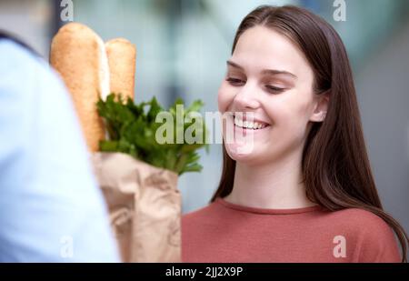 Donc reconnaissant pour les livraisons en ligne. Une jeune femme qui reçoit sa livraison d'épicerie. Banque D'Images