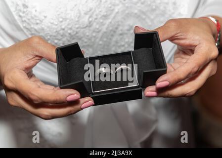 La boîte contenant les anneaux de mariage de la mariée et du marié est tenue entre ses mains. Banque D'Images