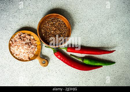 Graines de lin et sel rose dans les bols avec piment épicé frais sur la table Banque D'Images