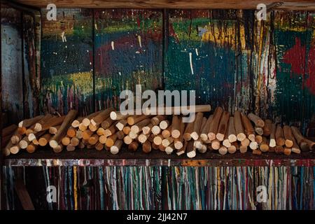 Des bouchons de bonde en bois empilés sur une étagère contre un mur de peinture coloré dans l'atelier de peinture de plusieurs petits bateaux empilés devant Trunnel Shed Banque D'Images