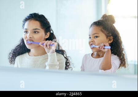 Nous commençons notre matinée par un souffle frais. Une jeune mère et une fille se brossent les dents dans une salle de bains à la maison. Banque D'Images