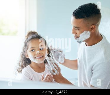 Rien n'est plus précieux que l'amour d'un père. Une petite fille et son père jouant autour avec la crème à raser dans une salle de bains à la maison. Banque D'Images