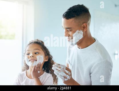 Je l'aime aussi. Une petite fille et son père jouant autour avec de la crème à raser dans une salle de bains à la maison. Banque D'Images