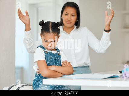 Je ne veux pas. Une jeune mère a l'air frustrée tout en aidant sa fille avec des devoirs à la maison. Banque D'Images