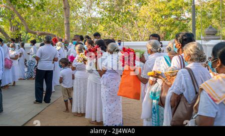 Anuradhapura, Sri Lanka - 03 31 2021: Des dévotés bouddhistes tenant des fleurs et d'autres offrandes, debout dans la ligne attendant leur chance à Jaya Sri Mah Banque D'Images