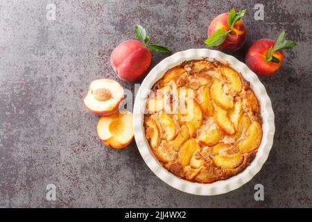 Cobbler à la pêche fraîchement cuit à proximité dans le plat de cuisson sur la table en béton gris. Vue horizontale du dessus Banque D'Images