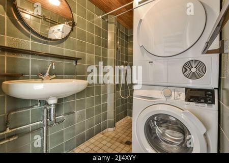 Salle de bains avec murs carrelés de vert et lavabo près du lave-linge et de la douche Banque D'Images