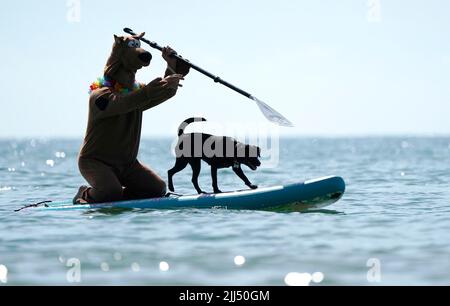 Un compétiteur avec son chien pratiquant avant les Dog Masters 2022 UK Dog Surfing Championships à Branksome Dene Chine Beach à Poole, Dorset. Date de la photo: Samedi 23 juillet 2022. Banque D'Images