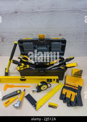 Instruments de construction et boîte à outils sur fond en bois. Tous les outils et une boîte avec des éléments jaunes. Place pour le texte ou le logo. Banque D'Images