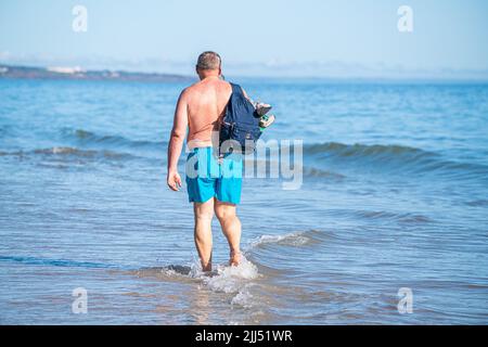 23 juillet 2022 : vue arrière d'un homme marchant sur la rive de l'océan avec un sac à dos Banque D'Images