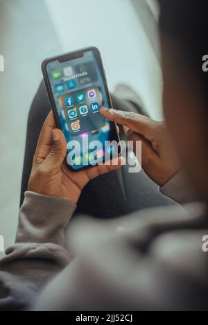 Mains d'une personne tenant un téléphone portable avec des icônes de réseaux sociaux affichées à l'écran Banque D'Images