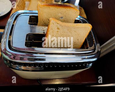 Délicieux pain blanc frais dans un grille-pain sur le point d'être grillé pendant le petit déjeuner Banque D'Images