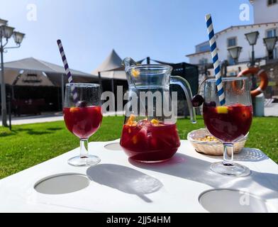 Pichet avec deux verres à côté rempli de délicieux sangria rouge d'été, de fruits frais et de deux pailles colorées Banque D'Images