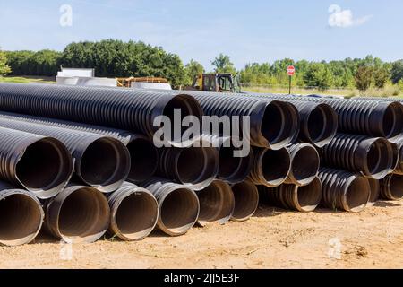 Sur le chantier de construction, de nouveaux tuyaux en plastique noir PVC empilés en rangées sont utilisés pour les systèmes de vidange Banque D'Images