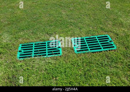 2 grilles de drainage de trou d'homme sur la pelouse avec l'herbe verte, le couvercle de fosse septique, le puisard cspool système de drainage environnement conception, vue de près éclairé par le soleil o Banque D'Images