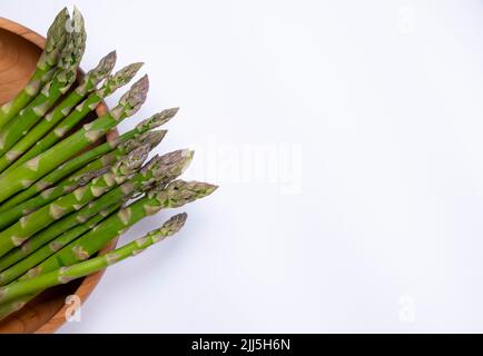 asperges vertes fraîches sur plaque en bois, sur fond blanc avec un endroit pour insérer le texte, copier l'espace concept de nourriture saine. Photo de haute qualité Banque D'Images