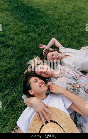 Bonne jeune femme couché avec des amis au parc Banque D'Images