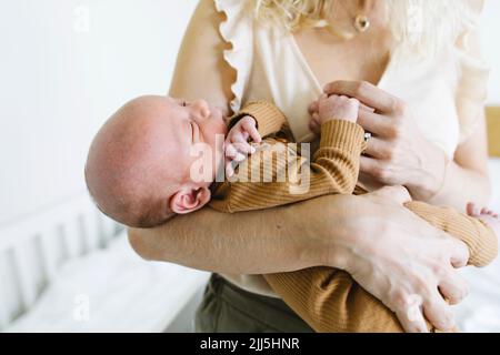 Mère portant bébé dans le bras à la maison Banque D'Images