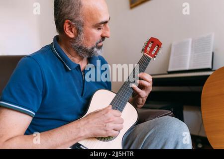 Homme mature jouant ukulele à la maison Banque D'Images