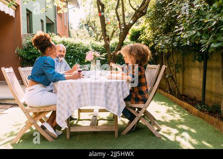 Femme souriante avec famille déjeuner à la table à manger dans la cour Banque D'Images
