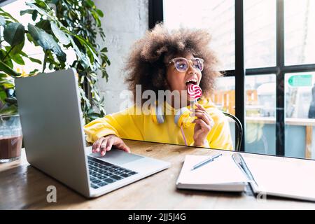 Une jeune fille qui se régale est assise avec un ordinateur portable dans un café Banque D'Images