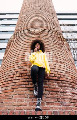 Une jeune fille qui se tient devant un mur de briques Banque D'Images