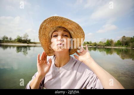 Femme mature portant un chapeau faisant des lèvres puckering le jour ensoleillé Banque D'Images