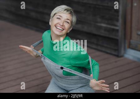 Femme gaie portant une salopette sur le porche Banque D'Images