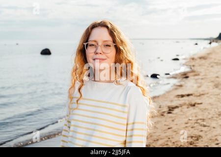 Femme souriante à la plage par beau temps Banque D'Images