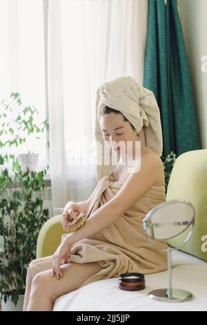 Femme massante avec une brosse sèche assise sur un canapé à la maison Banque D'Images