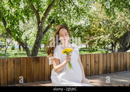 Femme enceinte avec des fleurs dans un parc public Banque D'Images