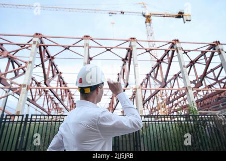 Ingénieur portant un casque de sécurité debout devant le cadre de construction Banque D'Images