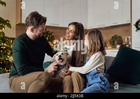 Famille souriante avec un chien qui profite de Noël ensemble à la maison Banque D'Images