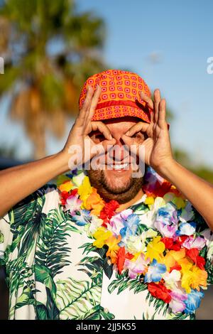 Homme souriant regardant à travers le cercle des doigts le jour ensoleillé Banque D'Images